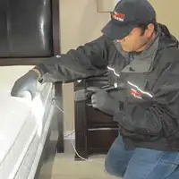 Bed bug inspection technician checking a mattress and bed frame for signs of infestation in Wichita, KS