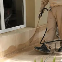 General pest control technician spraying exterior perimeter around a home in Wichita, KS