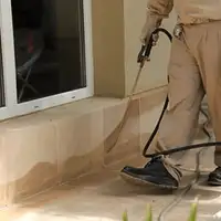 General pest control technician spraying exterior perimeter around a home in Wichita, KS