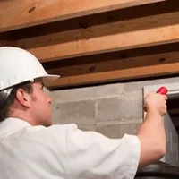 Termite inspection technician checking a basement wall and framing for termite activity in Wichita, KS
