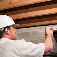 Termite inspection technician checking a basement wall and framing for termite activity in Wichita, KS